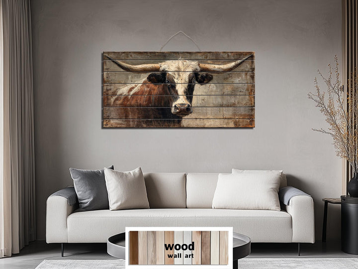 Rustic Texas longhorn bull portrait printed on horizontal wood planks above a modern sofa.