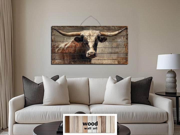 Rustic Texas longhorn bull portrait printed on horizontal wood planks above a modern sofa.