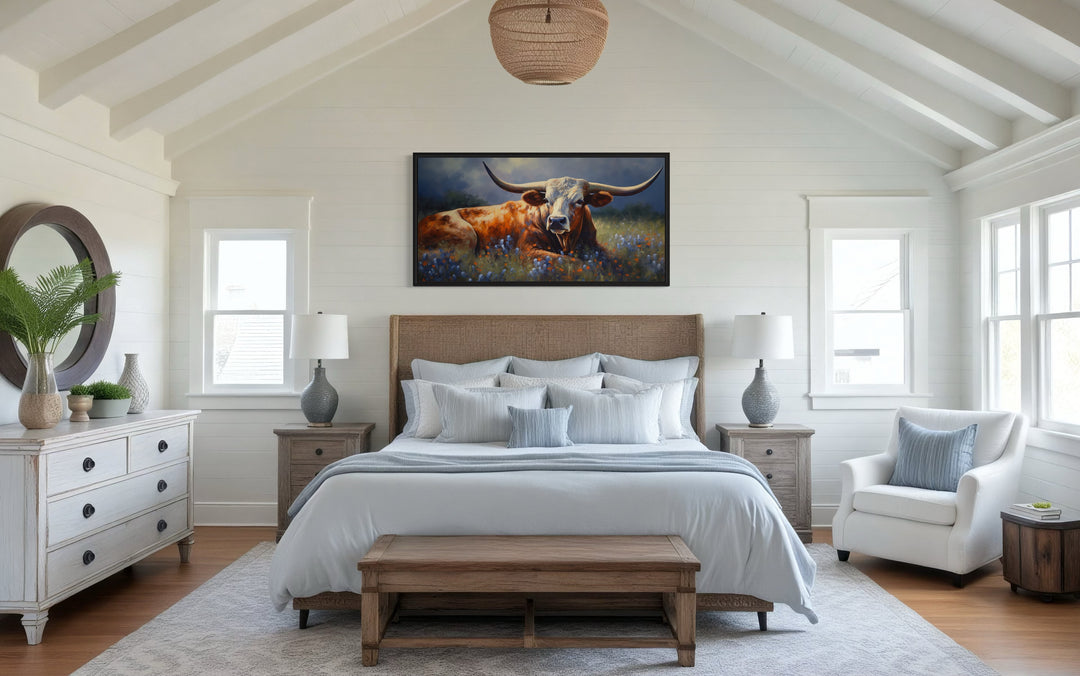 Texas Longhorn cow in a bluebonnet field canvas print framed above a bed in a rustic bedroom.