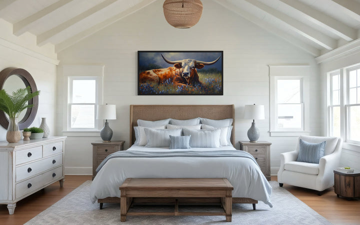 Texas Longhorn cow in a bluebonnet field canvas print framed above a bed in a rustic bedroom.