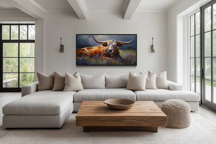 Framed canvas print of a Texas Longhorn in a bluebonnet field above a modern sofa.