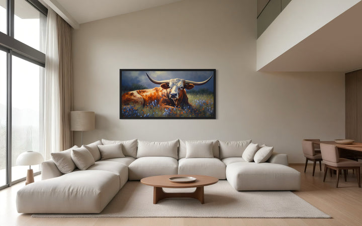 Framed canvas print of a Texas Longhorn cow in a bluebonnet field above a modern sectional sofa.