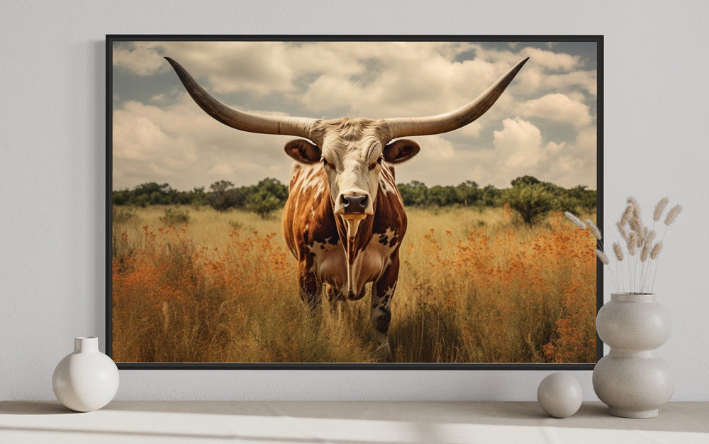 Framed canvas wall art of a Texas Longhorn cow in a field with muted sepia tones.