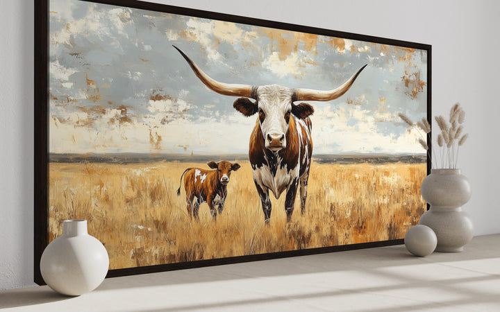 Framed canvas wall art of a Texas Longhorn cow and calf in a golden field under a soft blue sky.