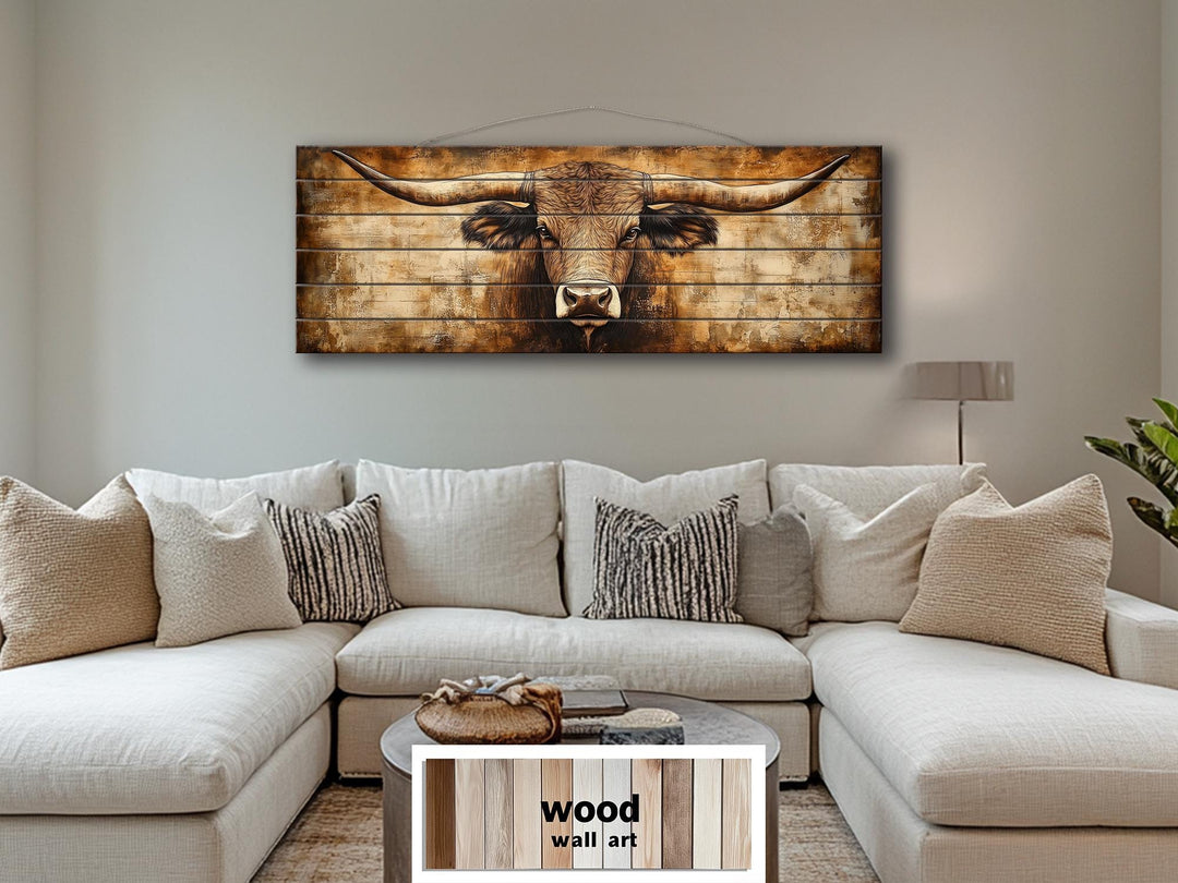 Texas longhorn bull portrait on horizontal wood planks hanging above a neutral sectional sofa.