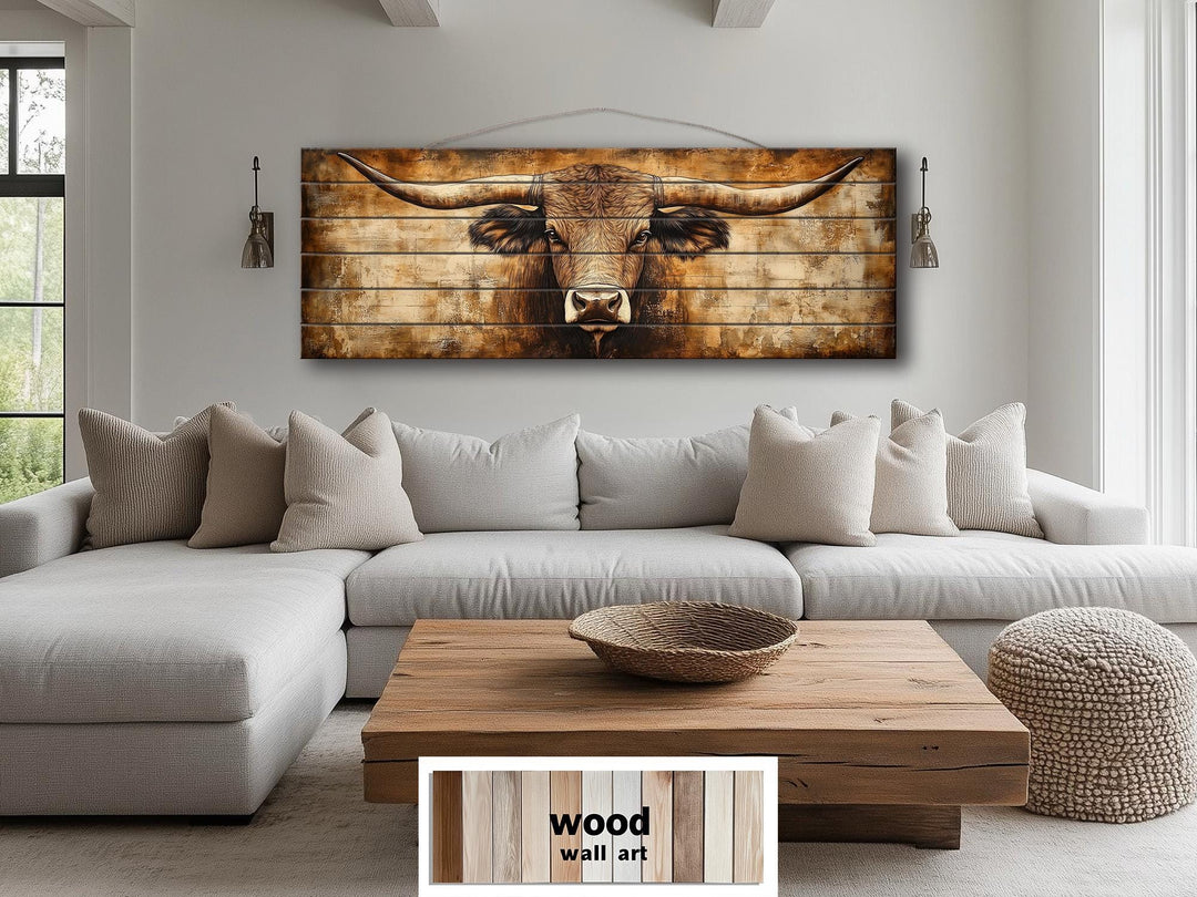 Horizontal wood wall art of a Texas longhorn bull in neutral brown tones above a modern sofa.