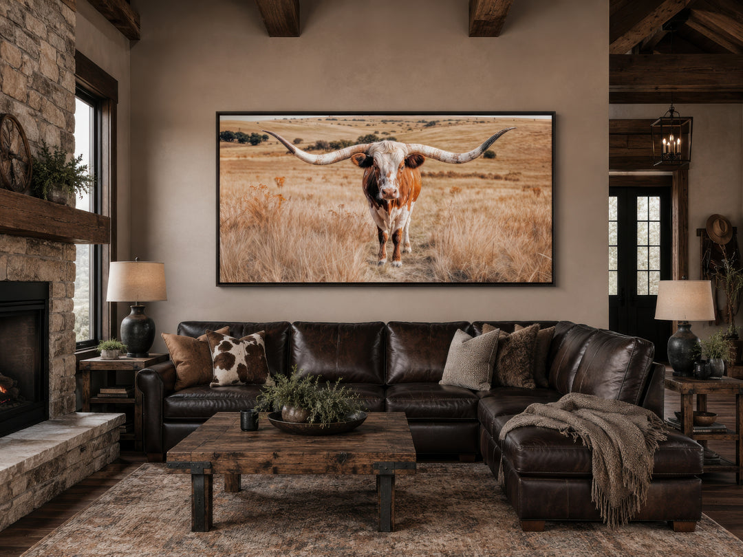 Texas Longhorn photography framed canvas wall art above a leather sofa in a rustic living room.