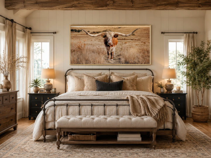 Texas Longhorn photography framed canvas wall art centered above a bed in a rustic bedroom.