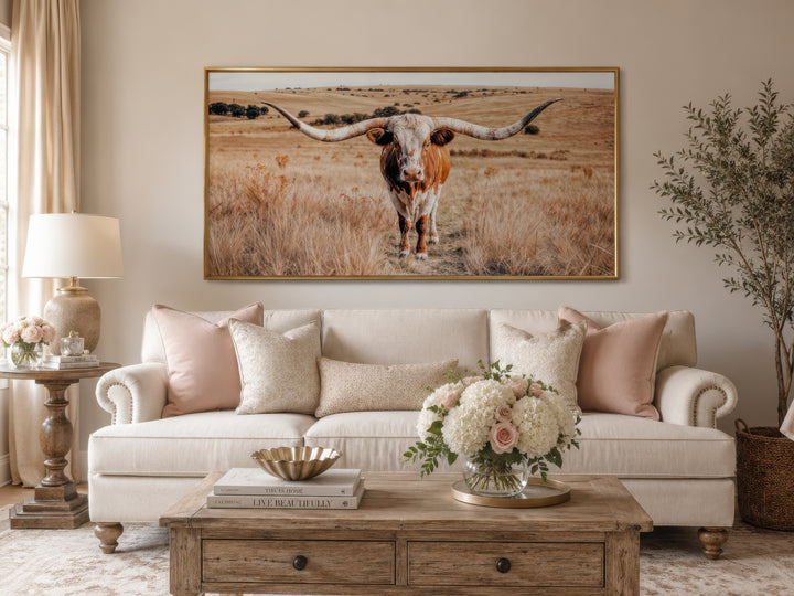 Texas Longhorn bull photography framed canvas wall art above a neutral sofa in a living room.