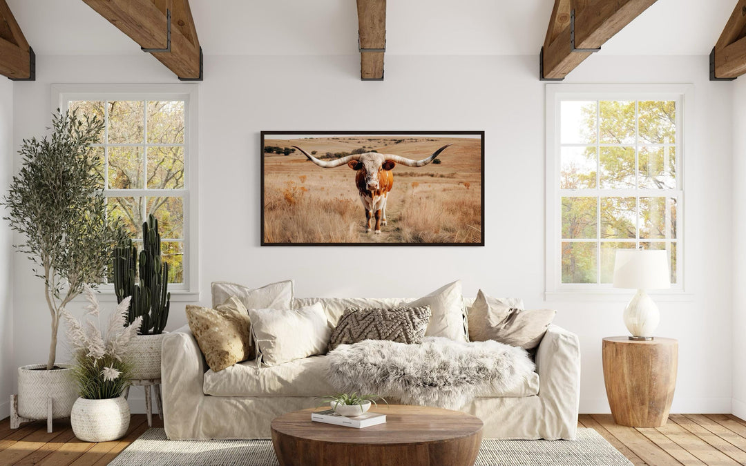 Texas Longhorn bull photography framed canvas wall art centered above a neutral sofa in a living room