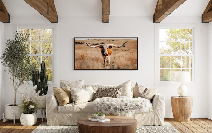 Texas Longhorn bull photography framed canvas wall art centered above a neutral sofa in a living room