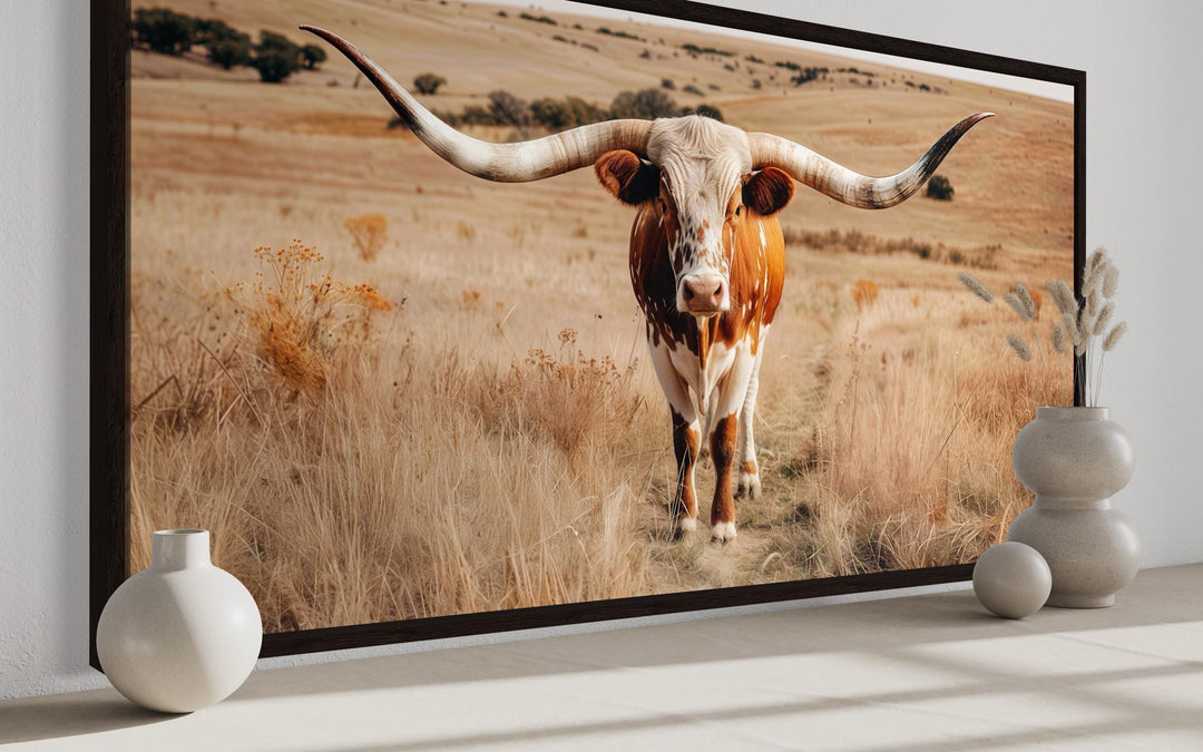 Framed canvas wall art of a Texas longhorn bull standing in a golden ranch landscape.