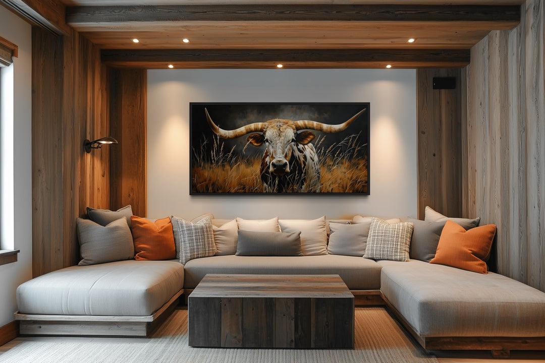 Framed canvas wall art of a Texas Longhorn steer in grass, hung above a modern sectional sofa.