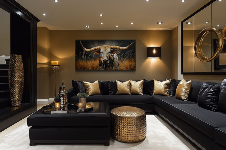 Framed canvas wall art of a Texas longhorn steer in grass above a black sectional sofa.