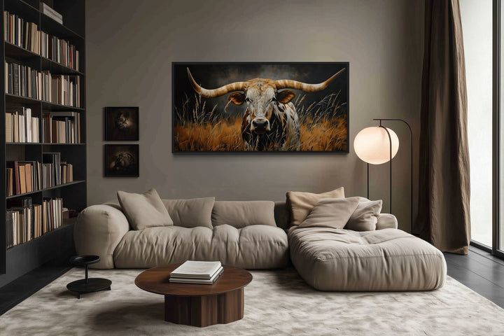 Framed canvas wall art of a Texas longhorn steer in grass, hanging in a rustic living room.