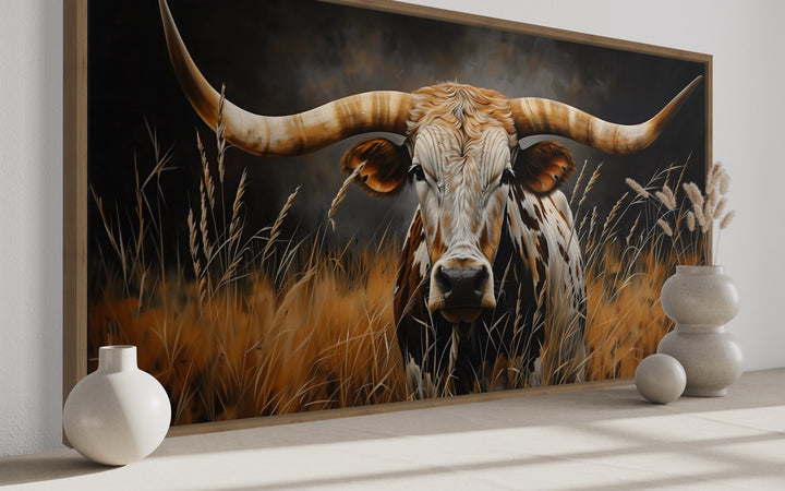 Framed canvas wall art of a Texas longhorn steer in a field of tall grass with a rustic finish.