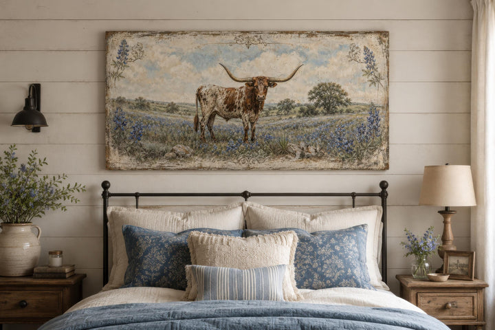 Rustic Texas Longhorn canvas print in a bluebonnet field above a farmhouse-style bed.