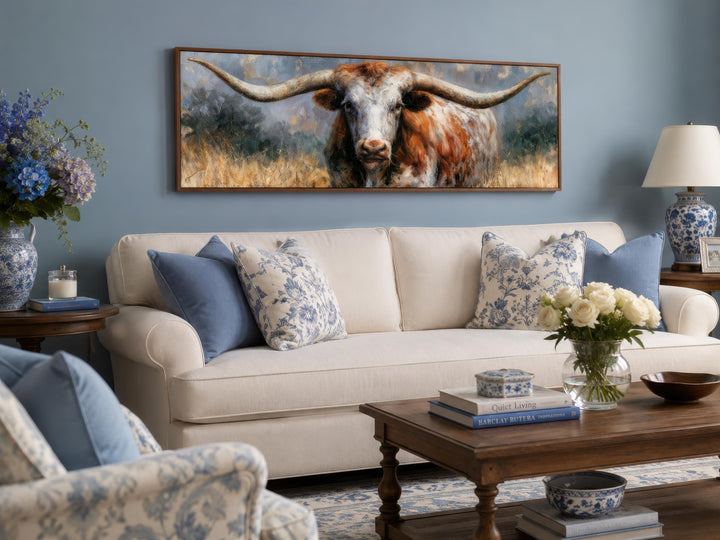 Texas Longhorn wall art canvas print in a long narrow frame above a white sofa in a living room.