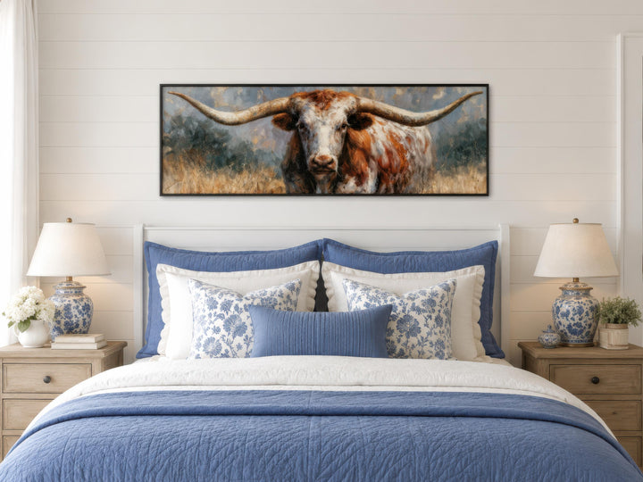 Texas Longhorn wall art canvas print in a long narrow frame above a bed in a farmhouse bedroom.