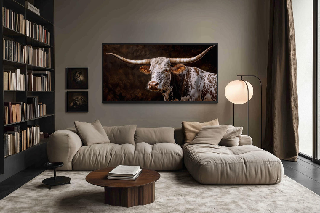 A large horizontal canvas print of a Texas Longhorn hangs above a modern sofa in a rustic living room.