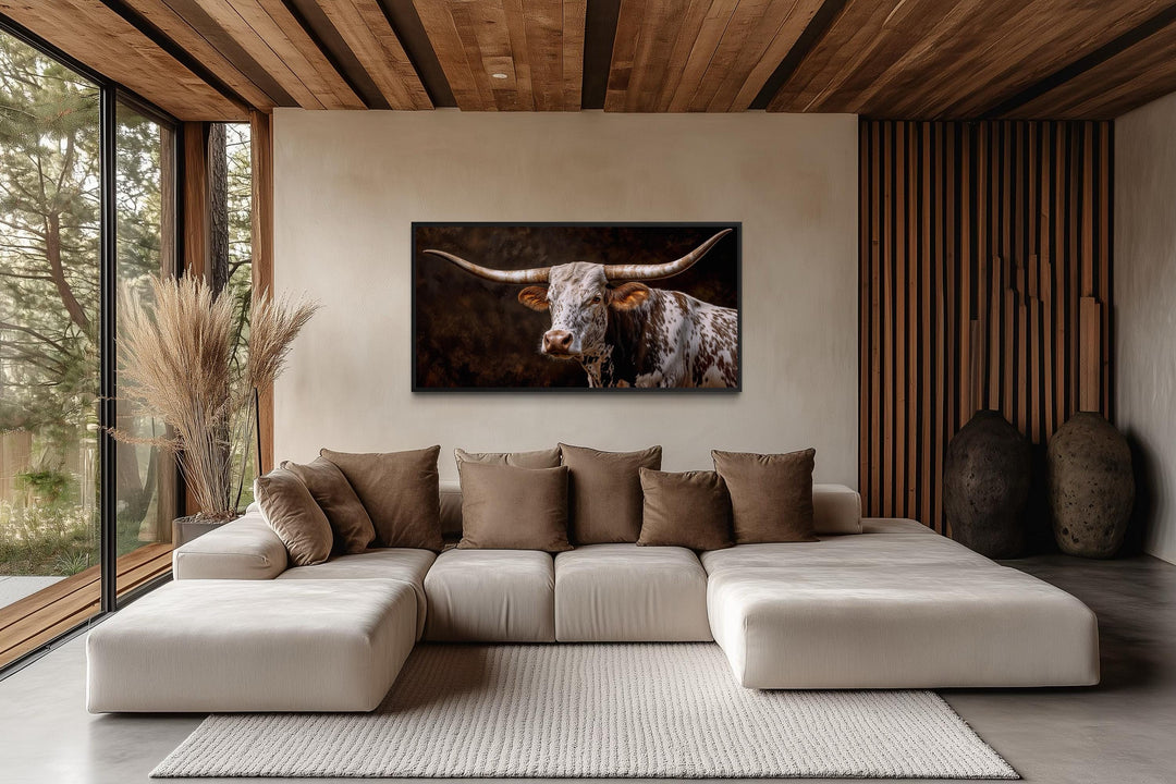 A framed canvas print of a Texas Longhorn hangs above a modern sectional in a rustic living room.