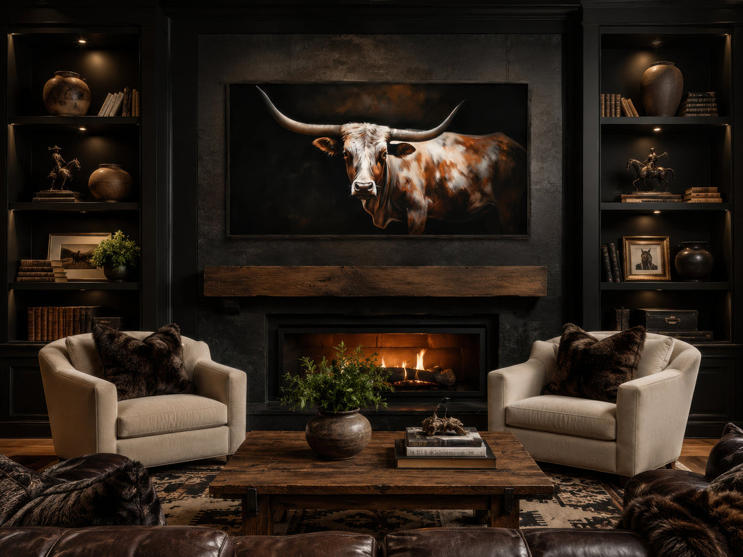 Extra large framed canvas wall art of a Texas Longhorn cow above a fireplace in a rustic room.