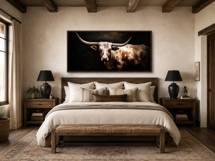 Extra large framed canvas wall art of a Texas Longhorn cow hanging above a bed in a rustic bedroom.