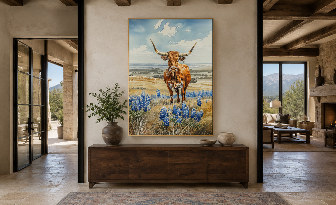 Vertical framed canvas wall art of a Texas longhorn cow in a field of bluebonnets above a sideboard.