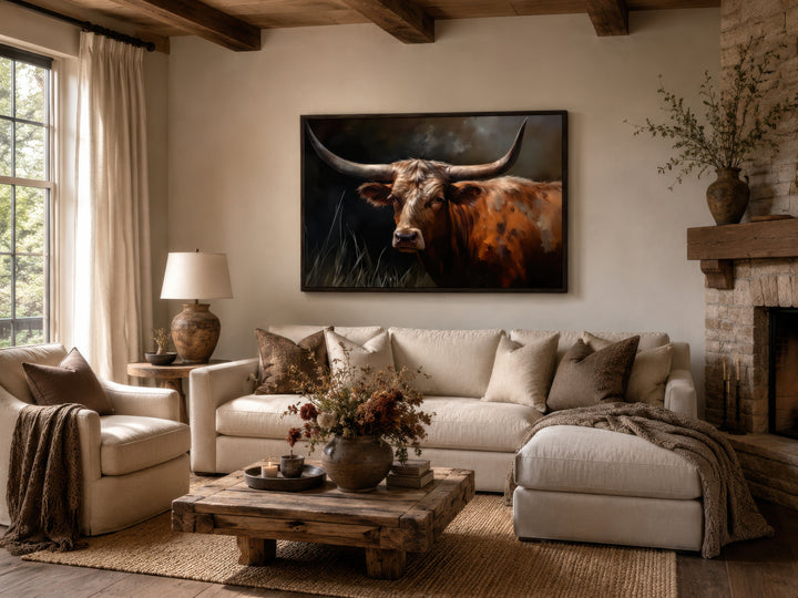 Framed canvas wall art of a brown Texas Longhorn cow hanging above a sofa in a rustic living room.