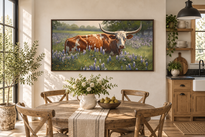 Framed canvas wall art of a Texas Longhorn cow in a field of bluebonnets above a dining table.