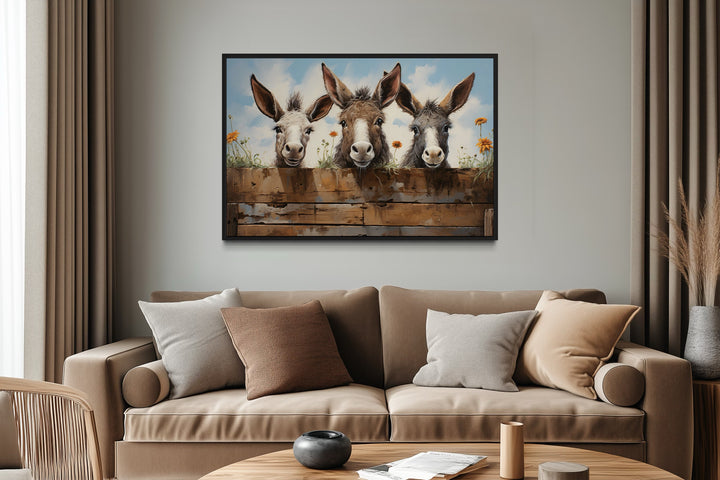 Three funny donkeys peeking over a wooden fence in a framed farmhouse canvas wall art.