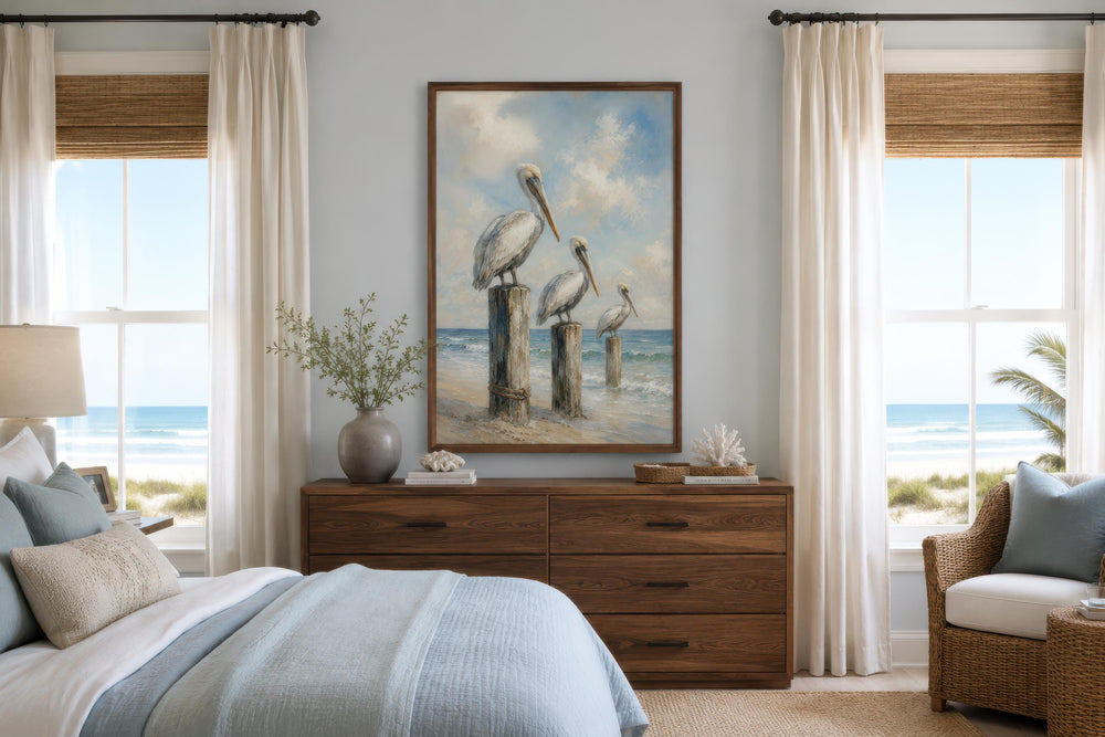 Three pelicans on dock posts coastal canvas wall art above a wooden dresser in a beach bedroom.