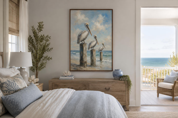 Three Pelicans on Dock Posts Coastal Canvas Wall Art hanging above a wooden dresser in a bedroom.