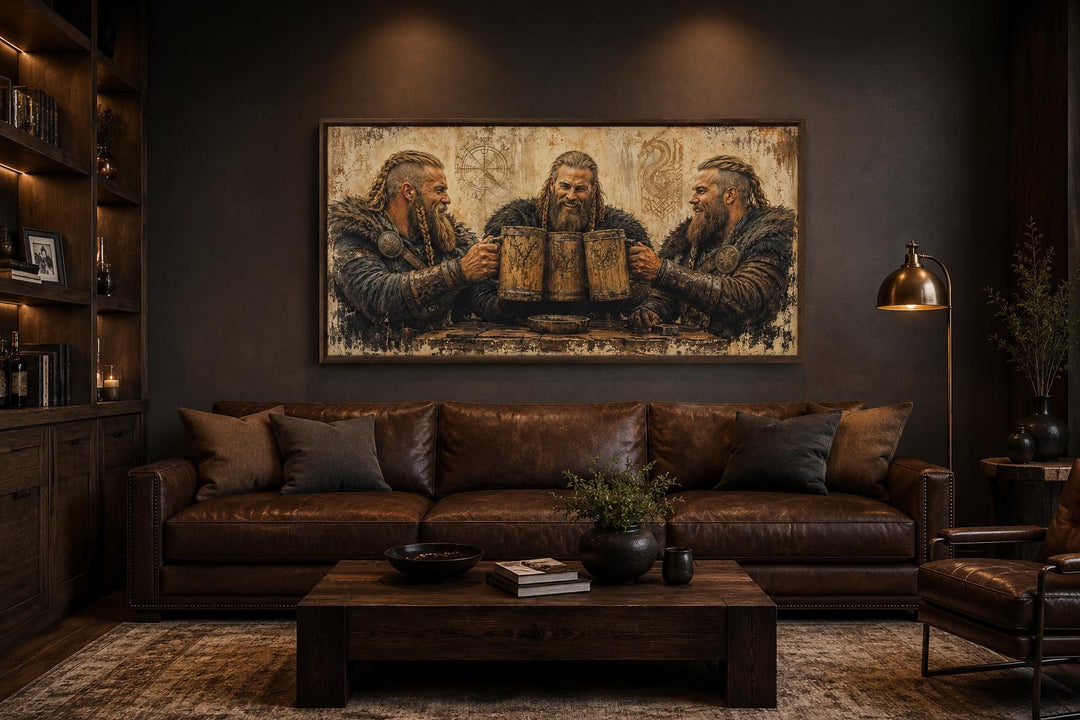 Three Vikings drinking beer canvas wall art hanging above a brown leather sofa in a rustic room.