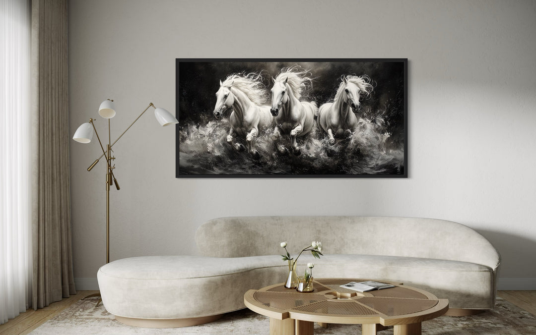 Three White Horses Running Framed Canvas Wall Art above a modern curved sofa in a living room.