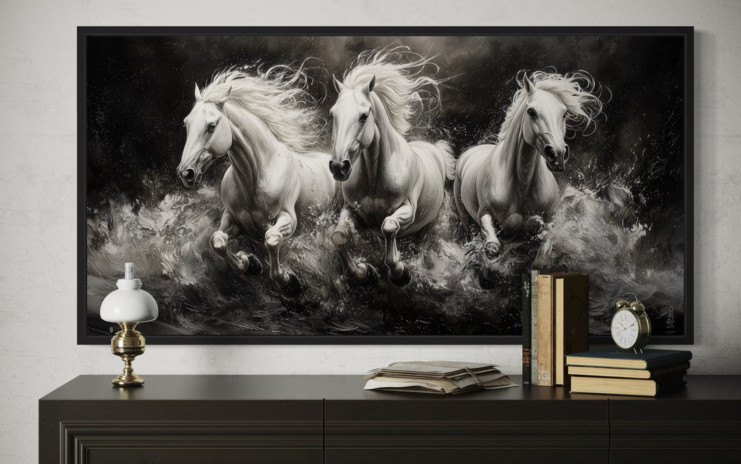 Three white horses running in water, framed canvas wall art above a dark wood console table.