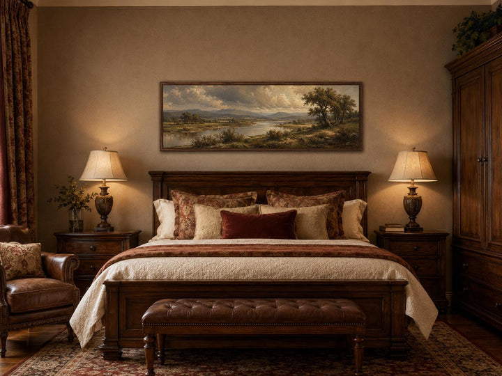 Traditional landscape canvas of a moody river valley above a dark wood bed in a classic bedroom.