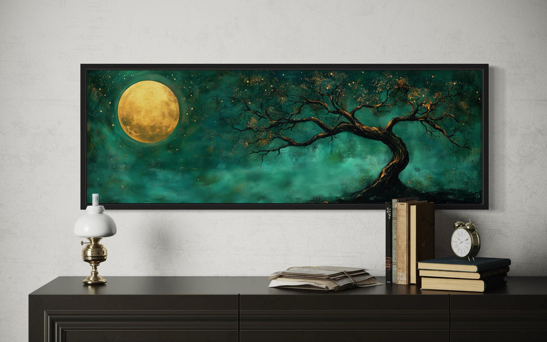 Tree and moon emerald green and gold long horizontal wall art framed above a dark wood console.