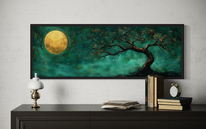 Tree and moon emerald green and gold long horizontal wall art framed above a dark wood console.