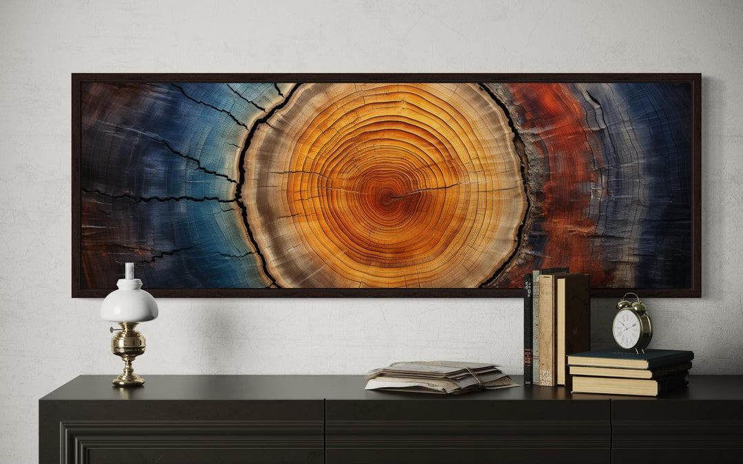 Tree ring horizontal canvas wall art with amber, orange, and navy blue tones above a dark console.
