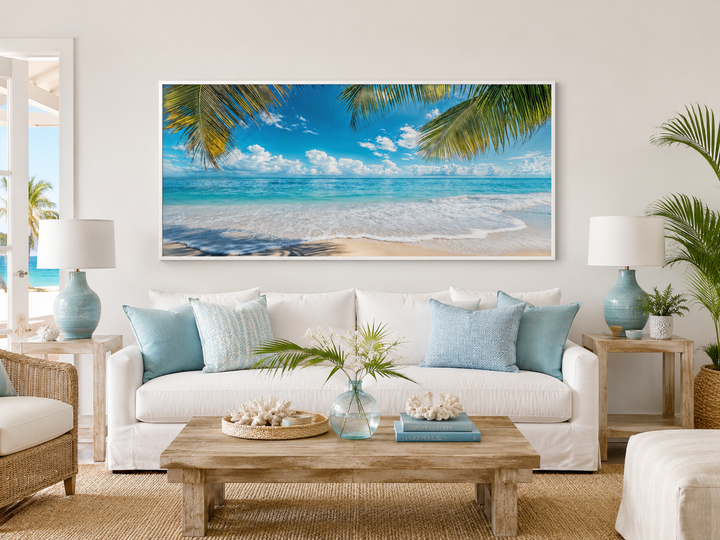 Tropical beach framed canvas wall art with palm trees and turquoise ocean over a white sofa.
