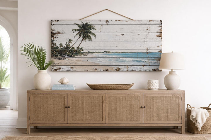 Tropical beach with palm trees distressed wood wall art hanging above a light wood console table.