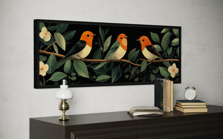 Panoramic canvas print of three colorful tropical birds perched on a branch among lush green leaves.