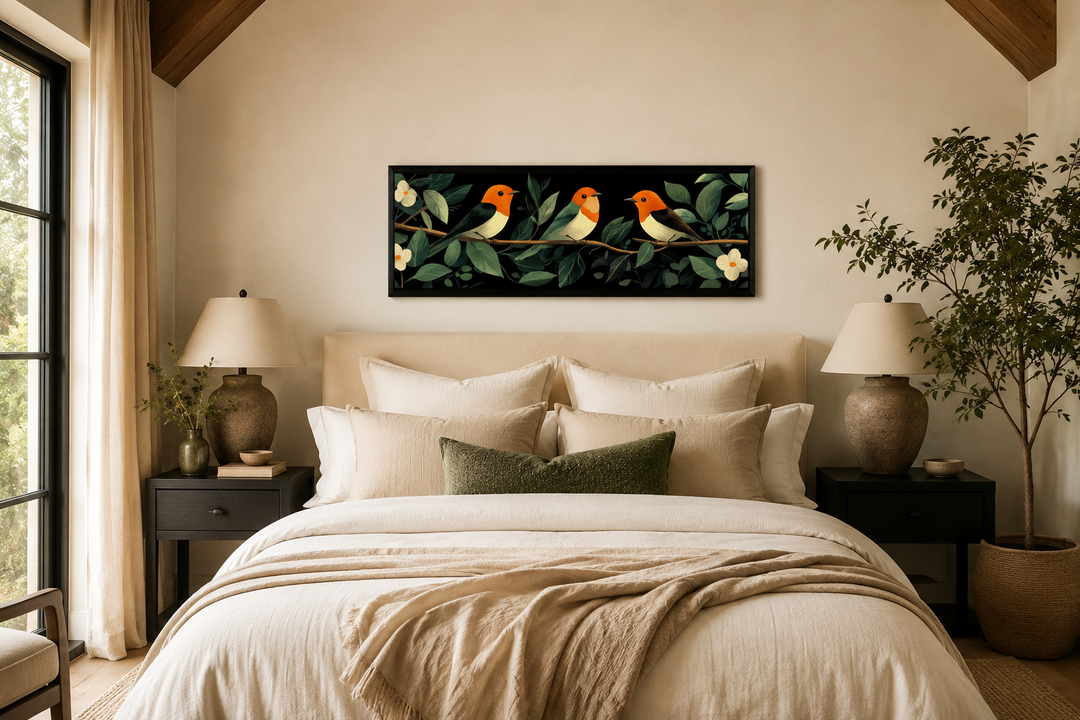 Long horizontal canvas print of three orange-headed birds on a branch above a neutral-toned bed.