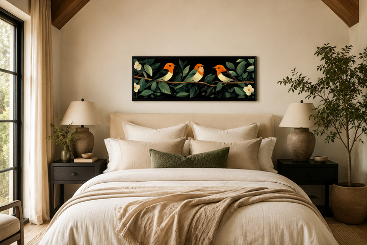Long horizontal canvas print of three orange-headed birds on a branch above a neutral-toned bed.