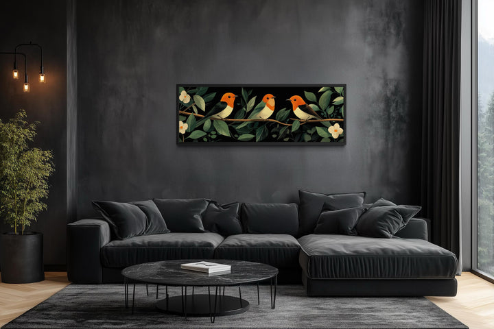 Tropical birds wall art canvas print featuring three colorful birds on a branch above a black sofa.