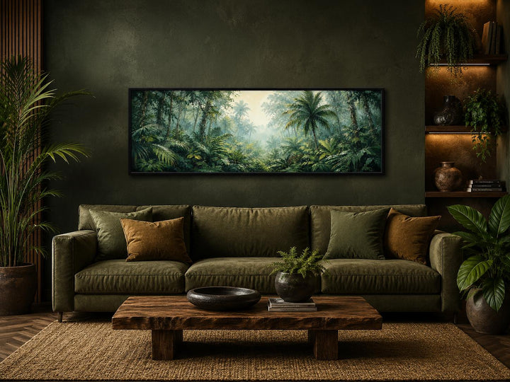 Tropical jungle canvas art with misty rainforest and palm trees above a green sofa.