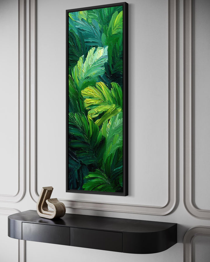 Vertical jungle botanical painting of tropical leaves on a narrow canvas print in a black frame.