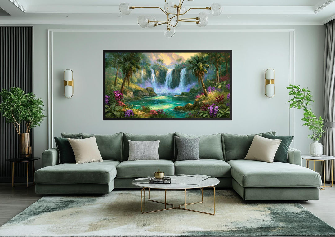 A wide horizontal canvas print of a lush tropical waterfall paradise hangs above a green sofa.