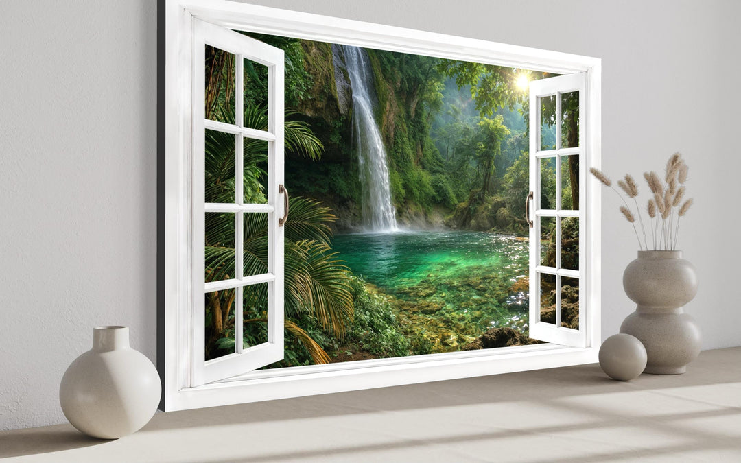 A canvas wall art piece depicting a tropical waterfall through an open white window frame.